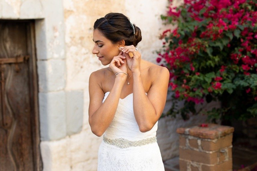 woman wearing wedding day jewelry including earrings, bracelets and necklace