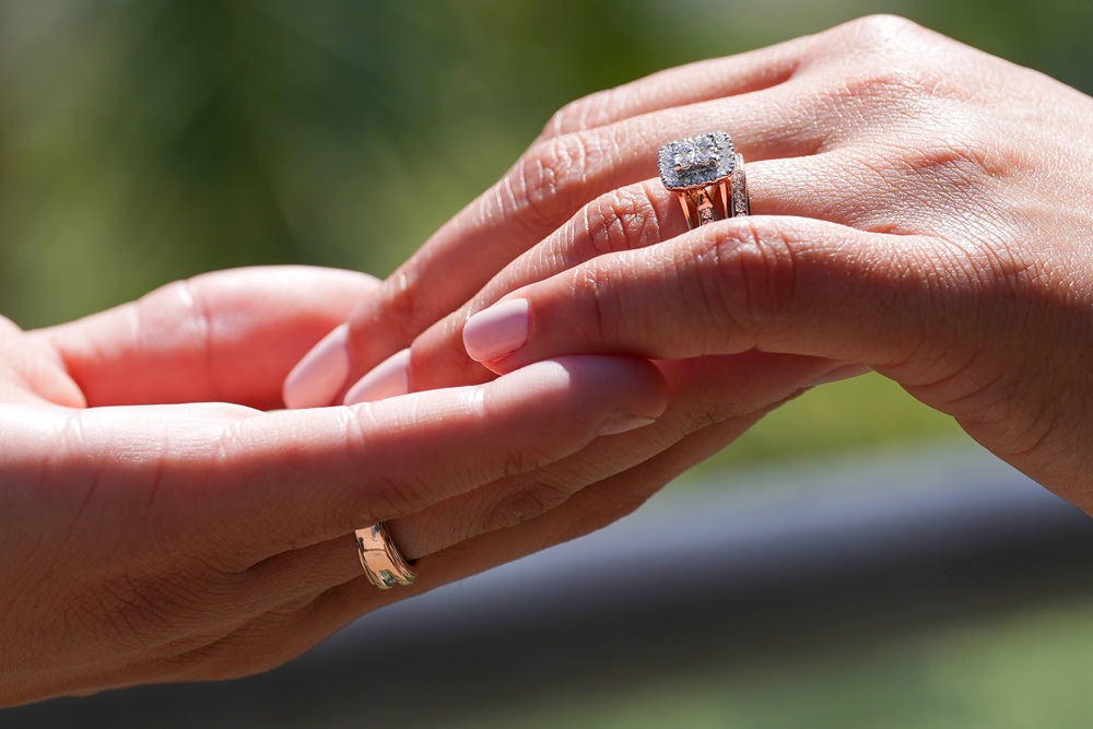 woman with engagement ring holding hands with man
