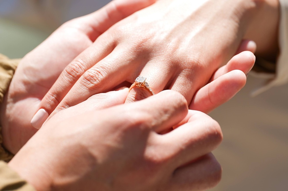 guy putting engagement ring on girls hand